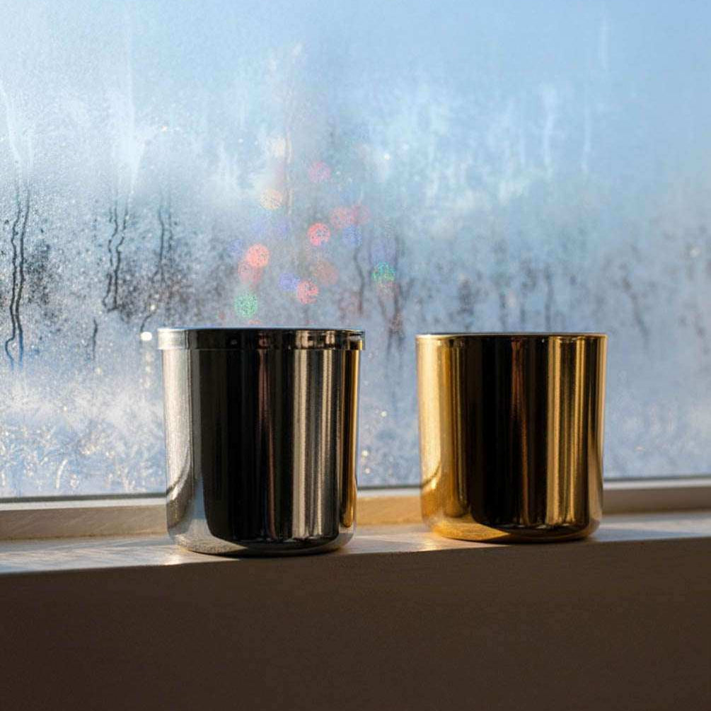 AEMBR metallic candle jars on a windowsill, with frosted glass and morning light