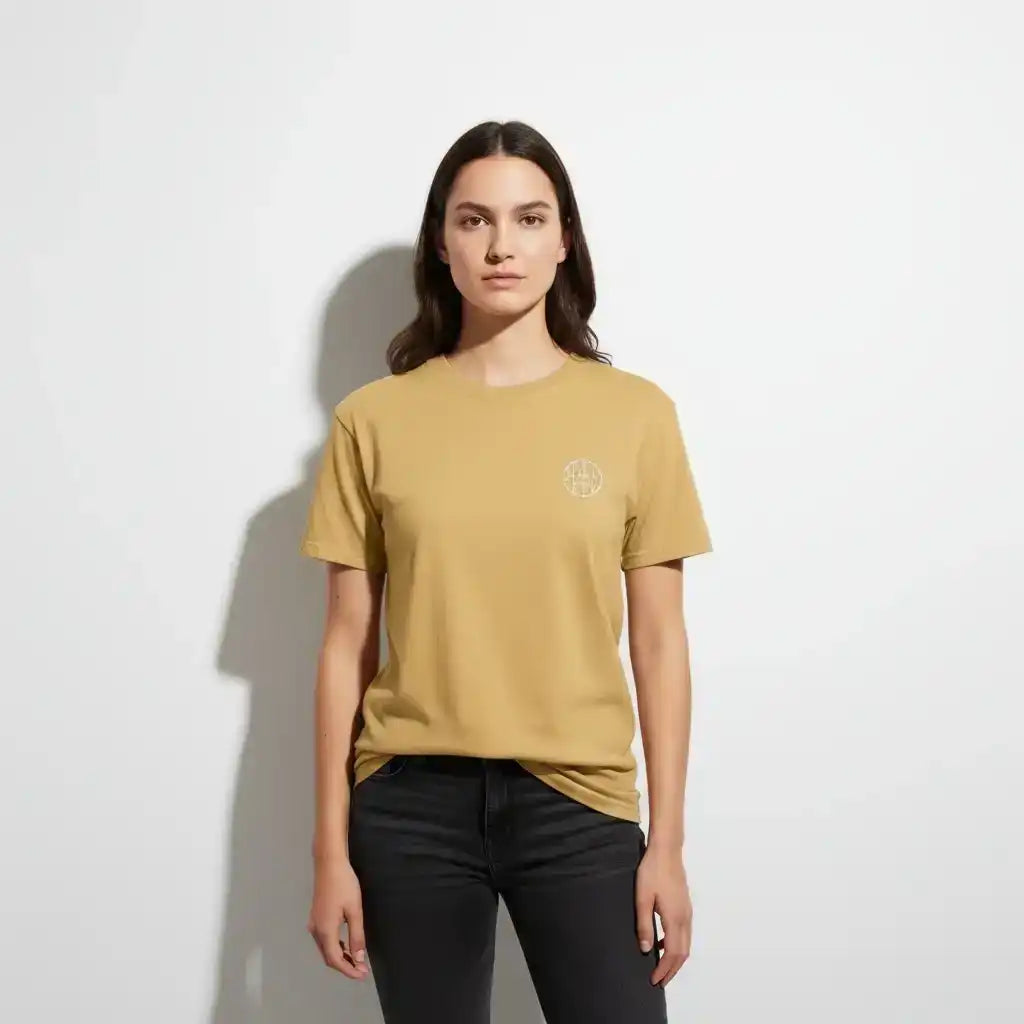 Woman wearing AEMBR tan t-shirt with small white logo, standing against white background