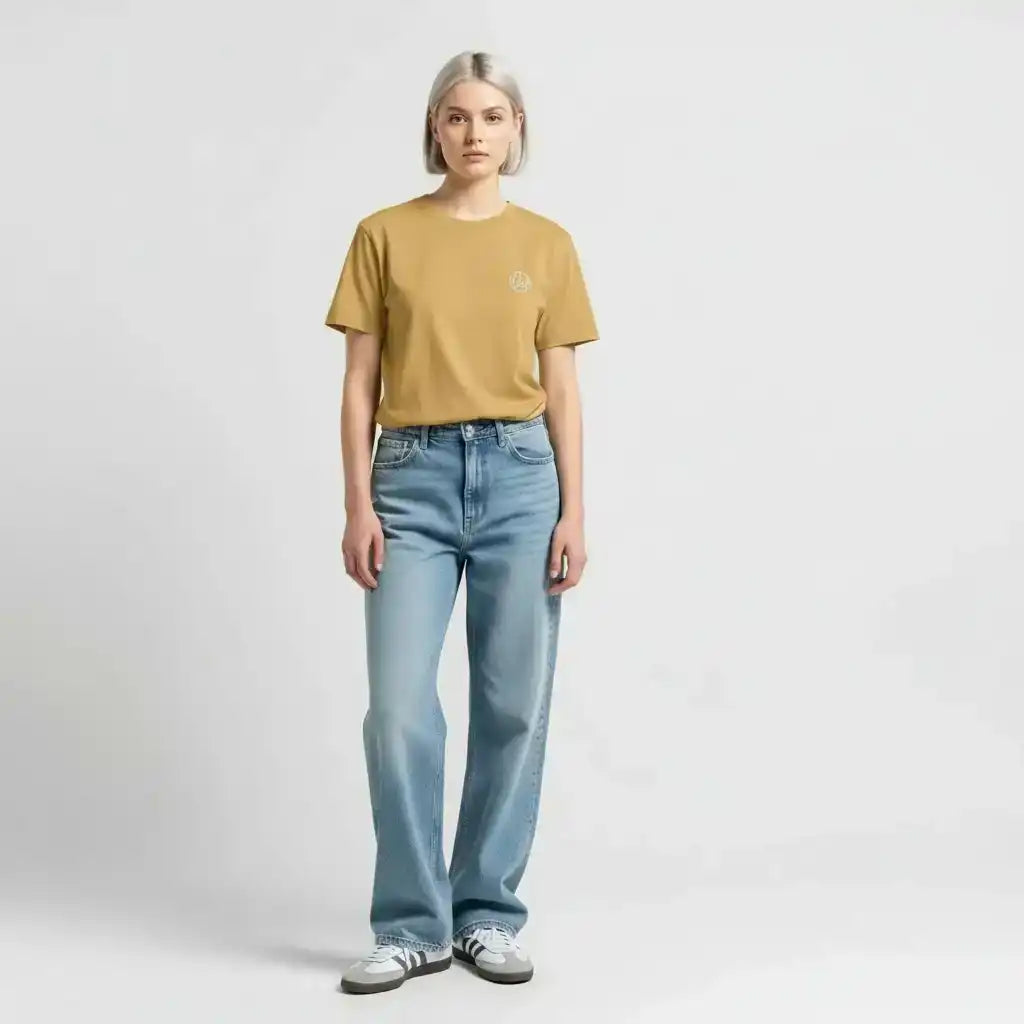 AEMBR model in mustard t-shirt with logo, light blue jeans and sneakers, minimalist background