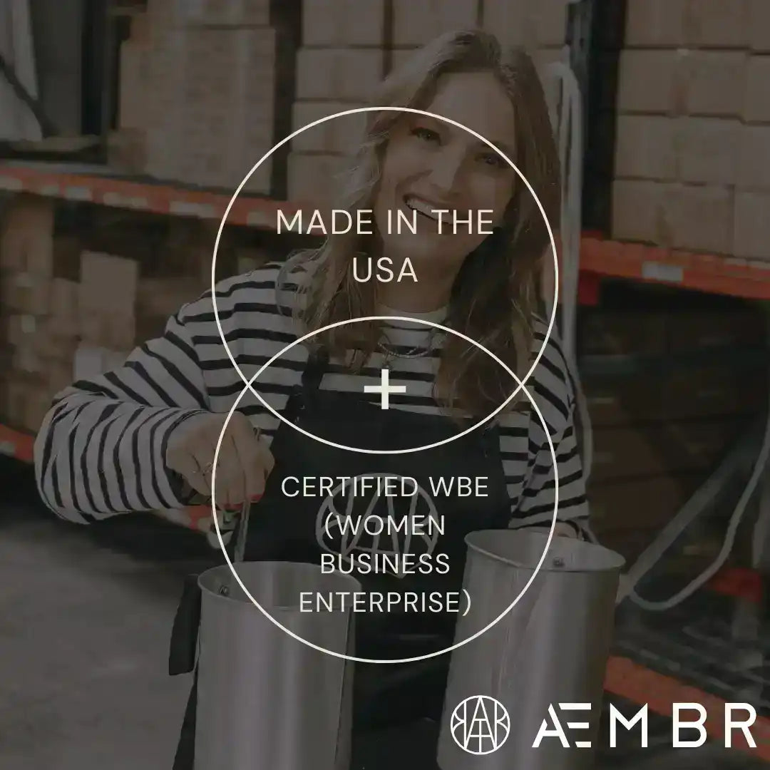 Smiling woman in striped shirt with apron holding metal containers in warehouse, AEMBR brand, Made in USA, Certified WBE
