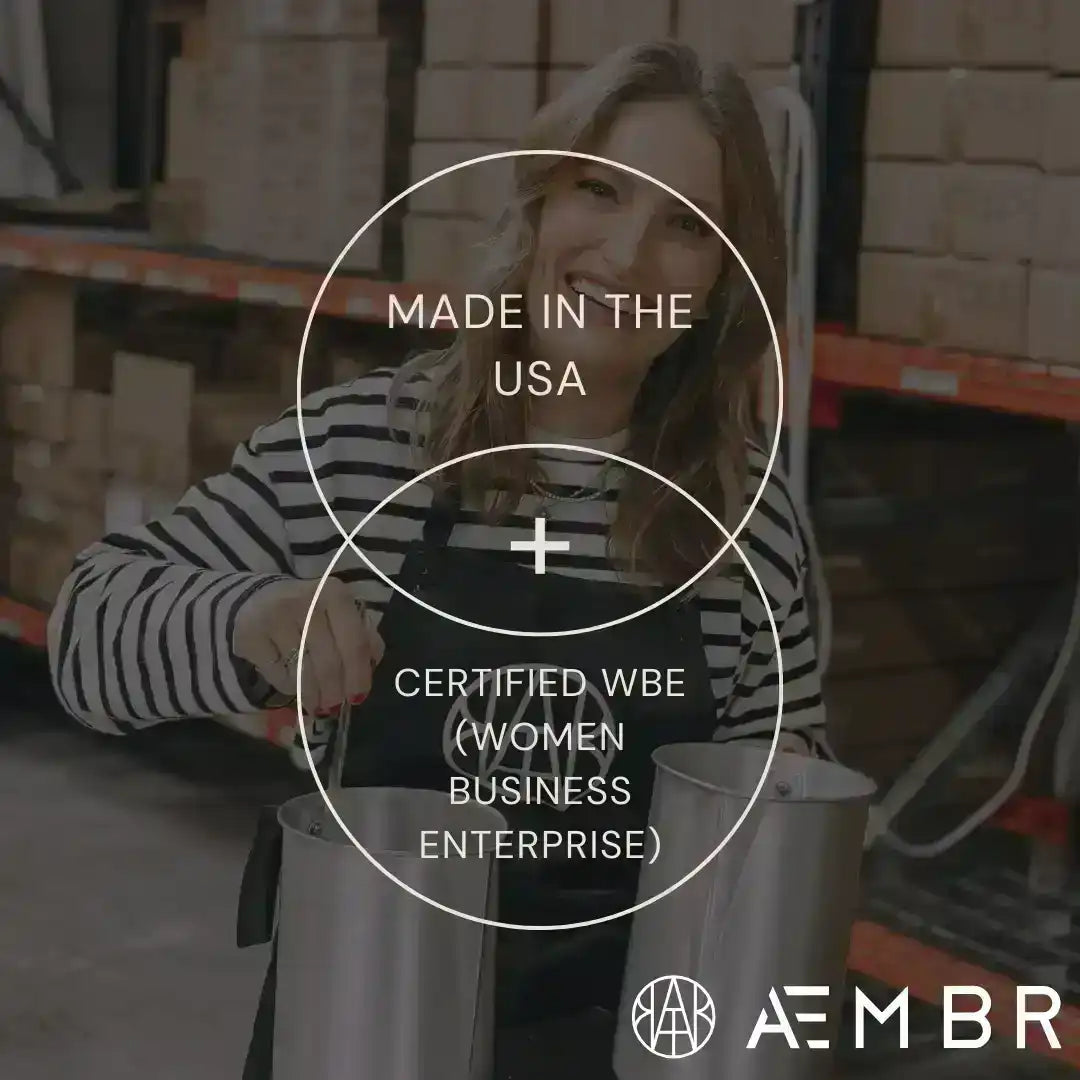 Smiling woman in striped shirt and AEMBR apron holding metal containers in warehouse, text: Made in the USA, Certified WBE (Women Business Enterprise).
