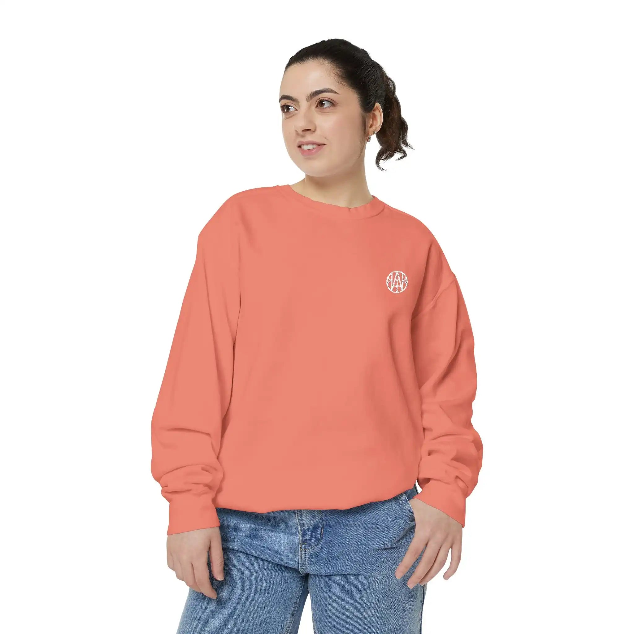 Woman wearing orange AEMBR sweatshirt with white logo and blue jeans on white background