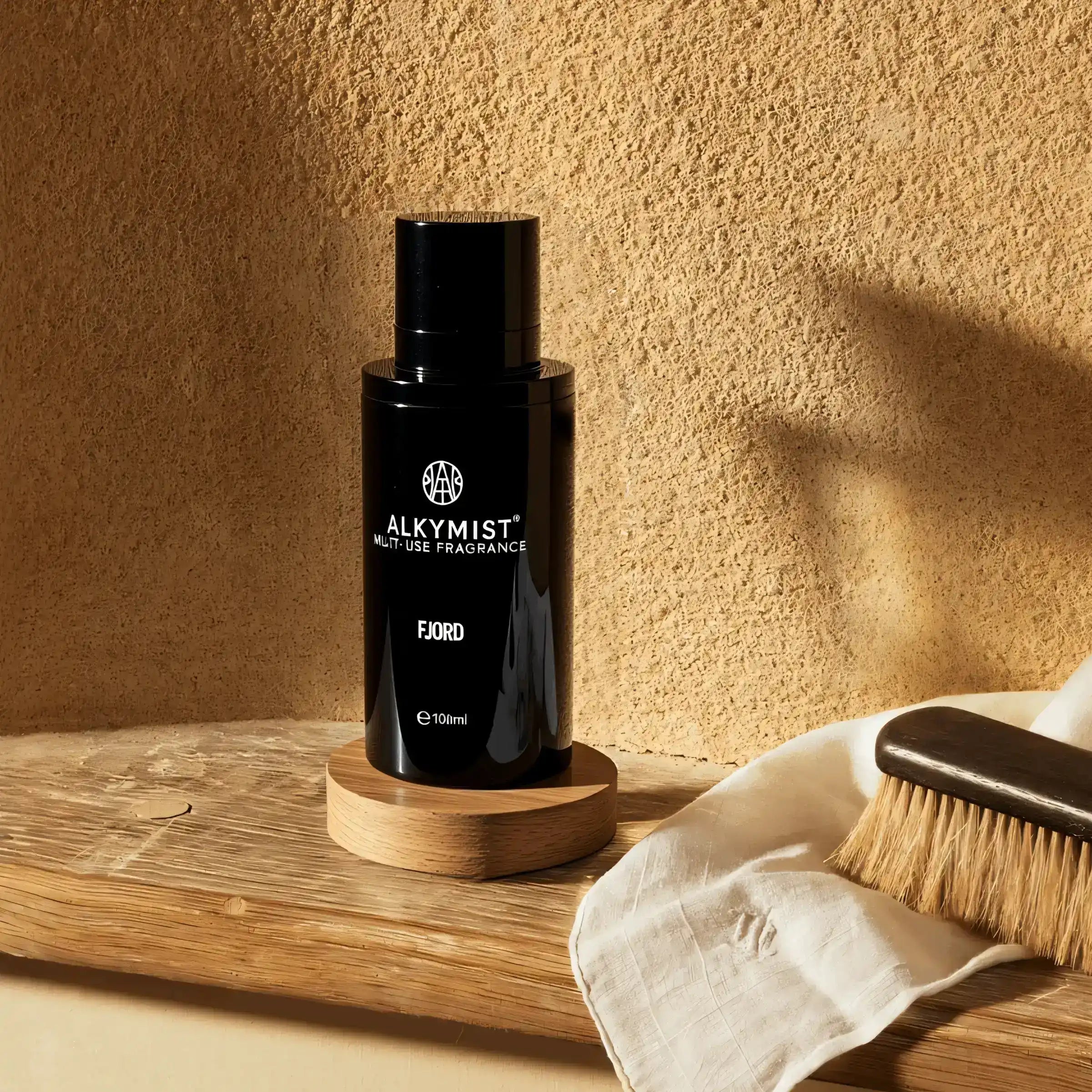 AEMBR AlkyMist multi-use fragrance bottle on wooden shelf with natural brush and cloth