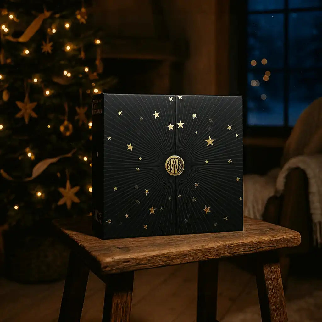 AEMBR gift box with gold stars on a wooden stool, holiday setting with Christmas tree