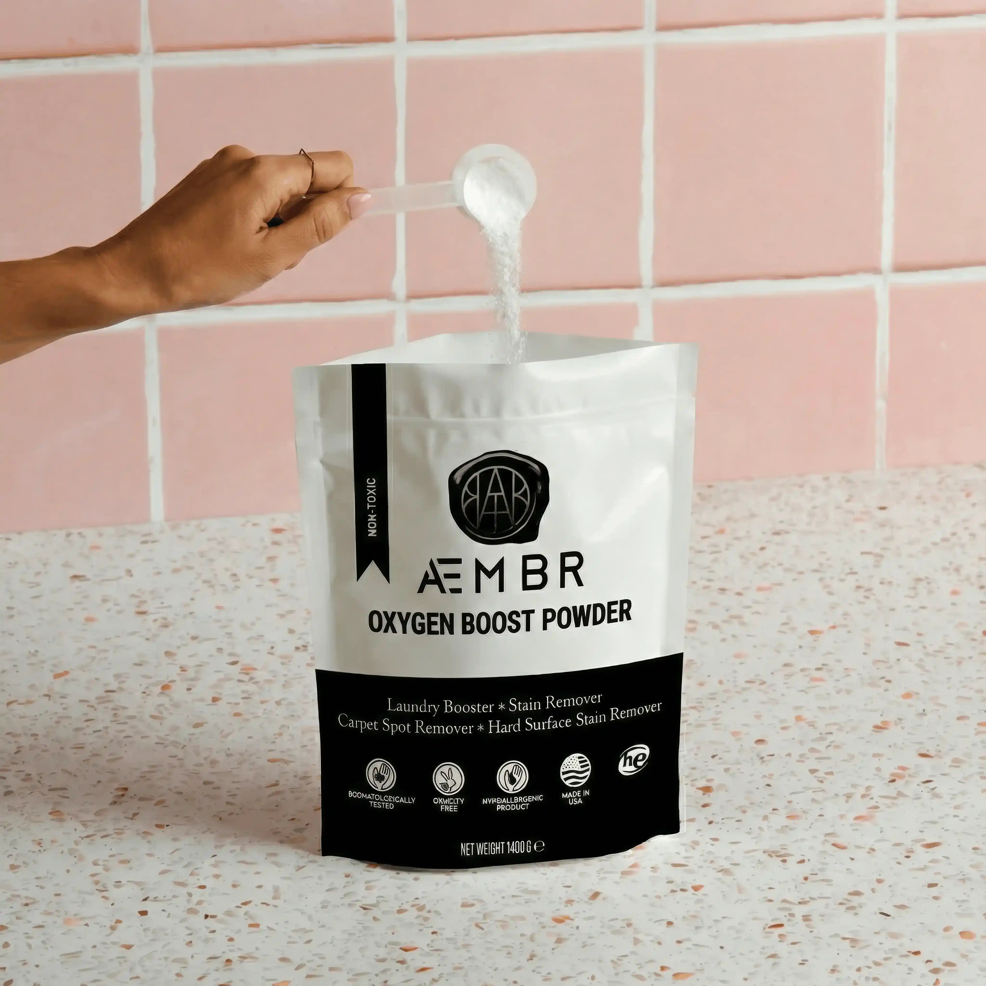 Person pouring non-toxic oxygen boost powder stain remover into AEMBR laundry bag