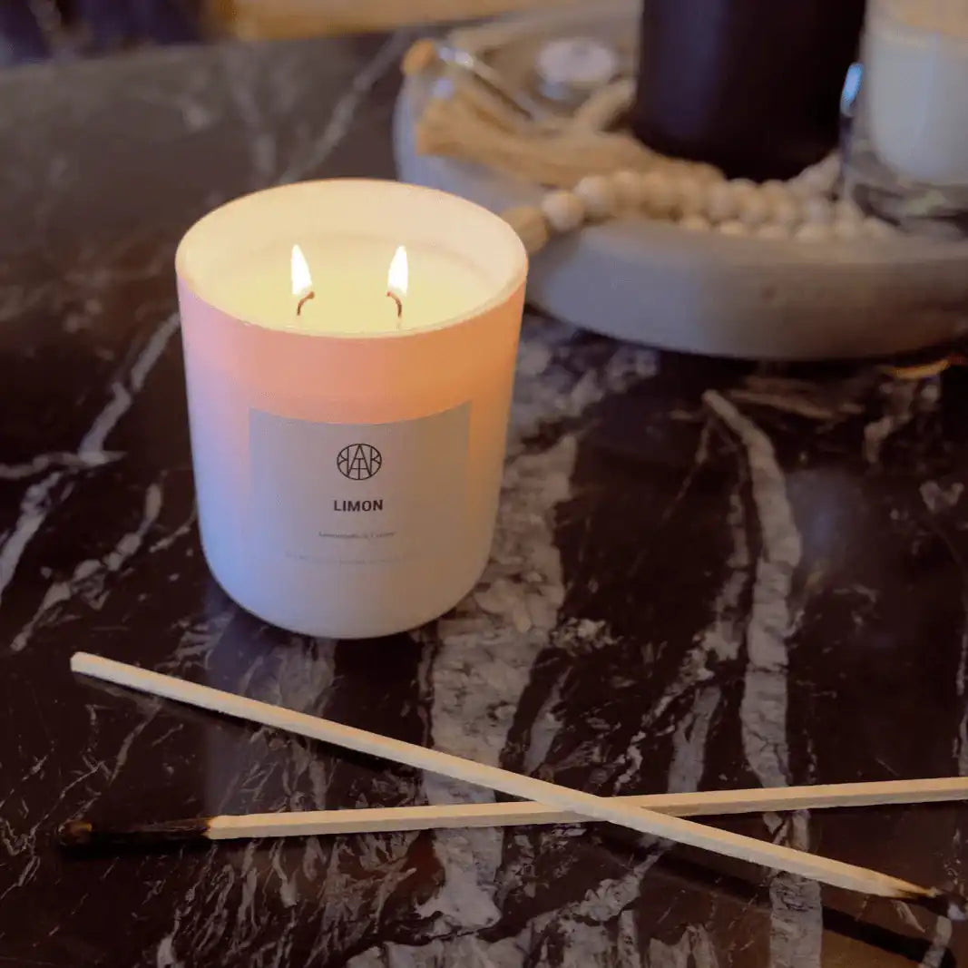 AEMBR Limon non-toxic candle burning on a dark marble surface with matches nearby