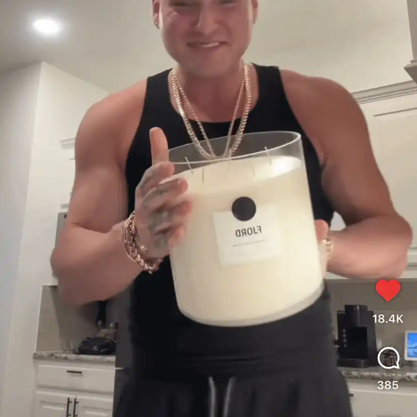 Smiling person holding a large non-toxic candle in a modern kitchen setting