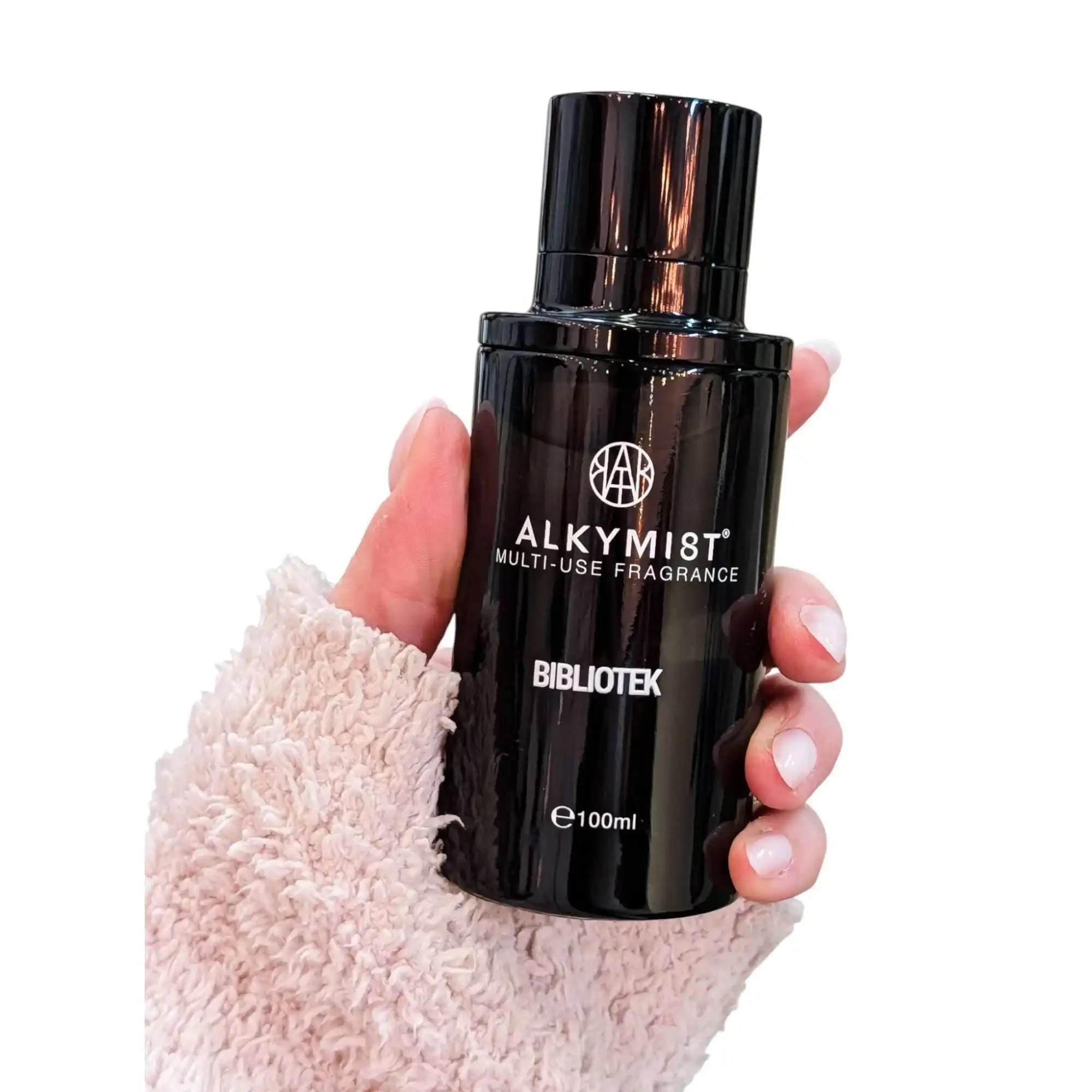 Hand holding AEMBR ALKYMI8T Bibliotek multi-use fragrance bottle, 100ml, on white background