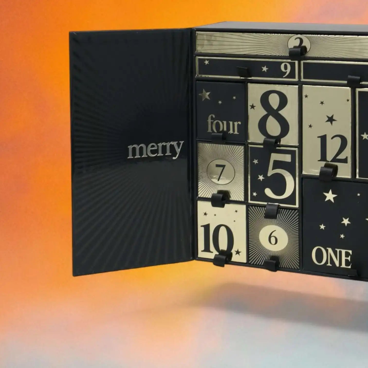 AEMBR luxury black and gold advent calendar with numbered compartments against an orange background