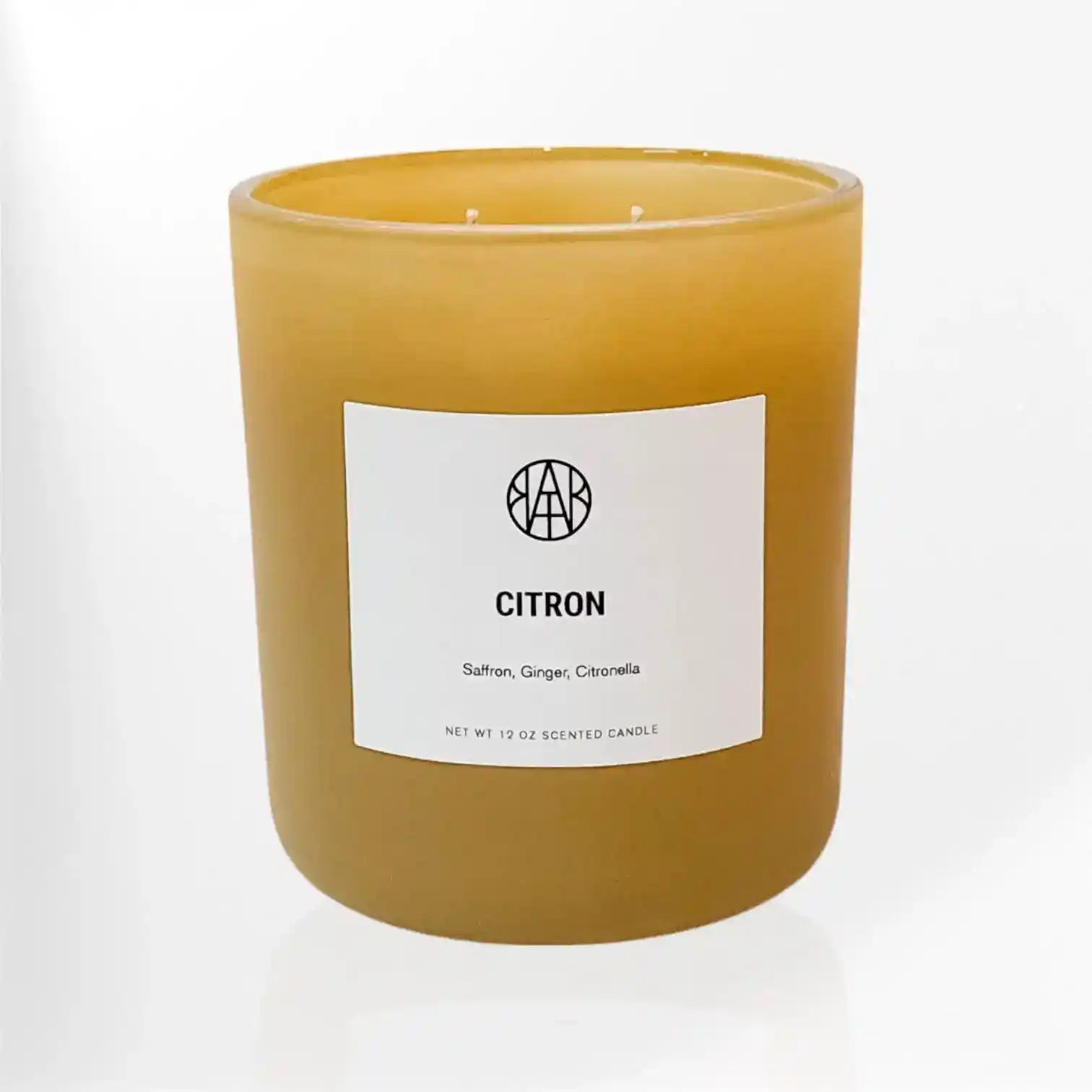 A lemon-scented Citron Candle by AEMBR with a simple glass holder and a lit wick, emitting a warm, inviting glow.