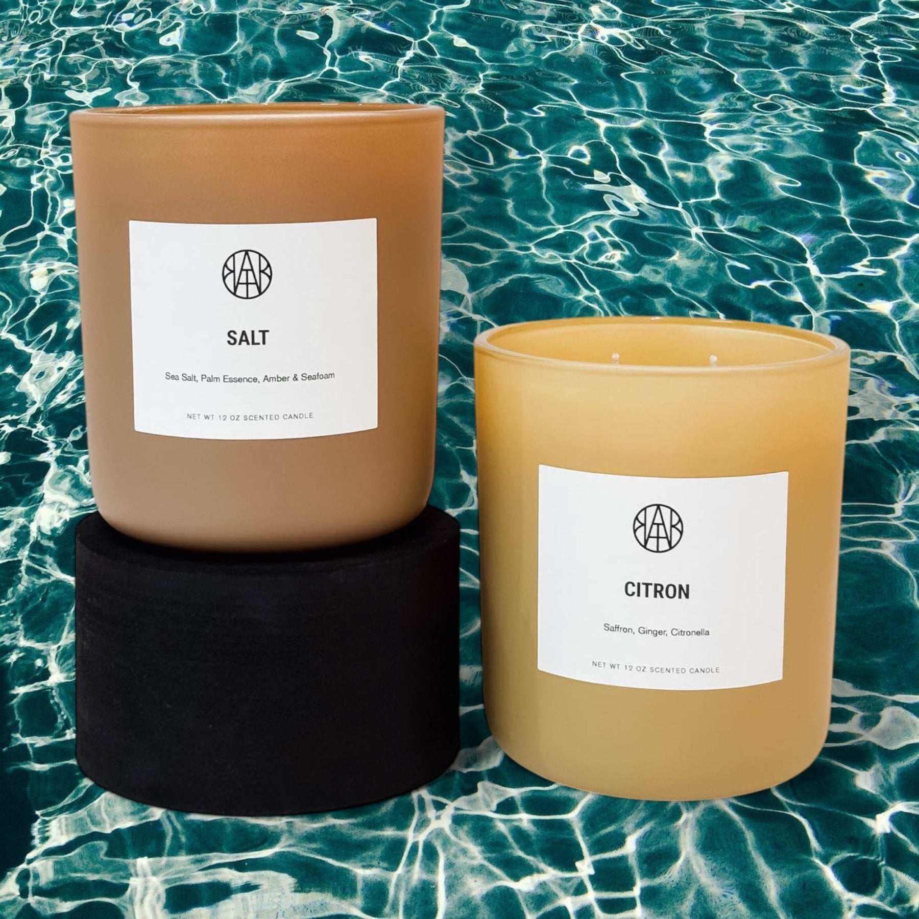 AEMBR Citron Candle showcasing a sleek glass container with a lit wick, emitting a fresh citrus scent.