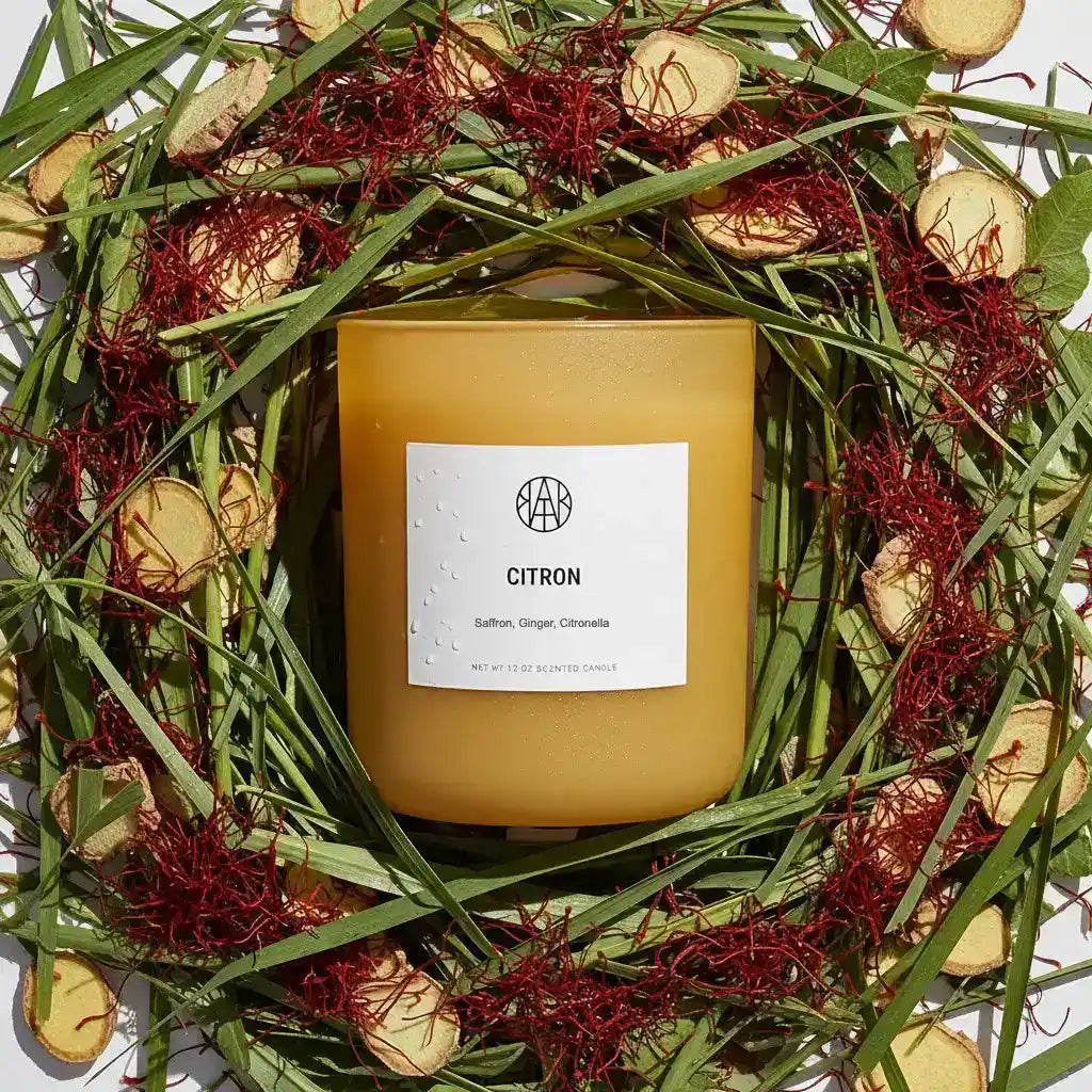 A citron-scented candle from AEMBR with a simple glass holder, emitting a warm, inviting glow.