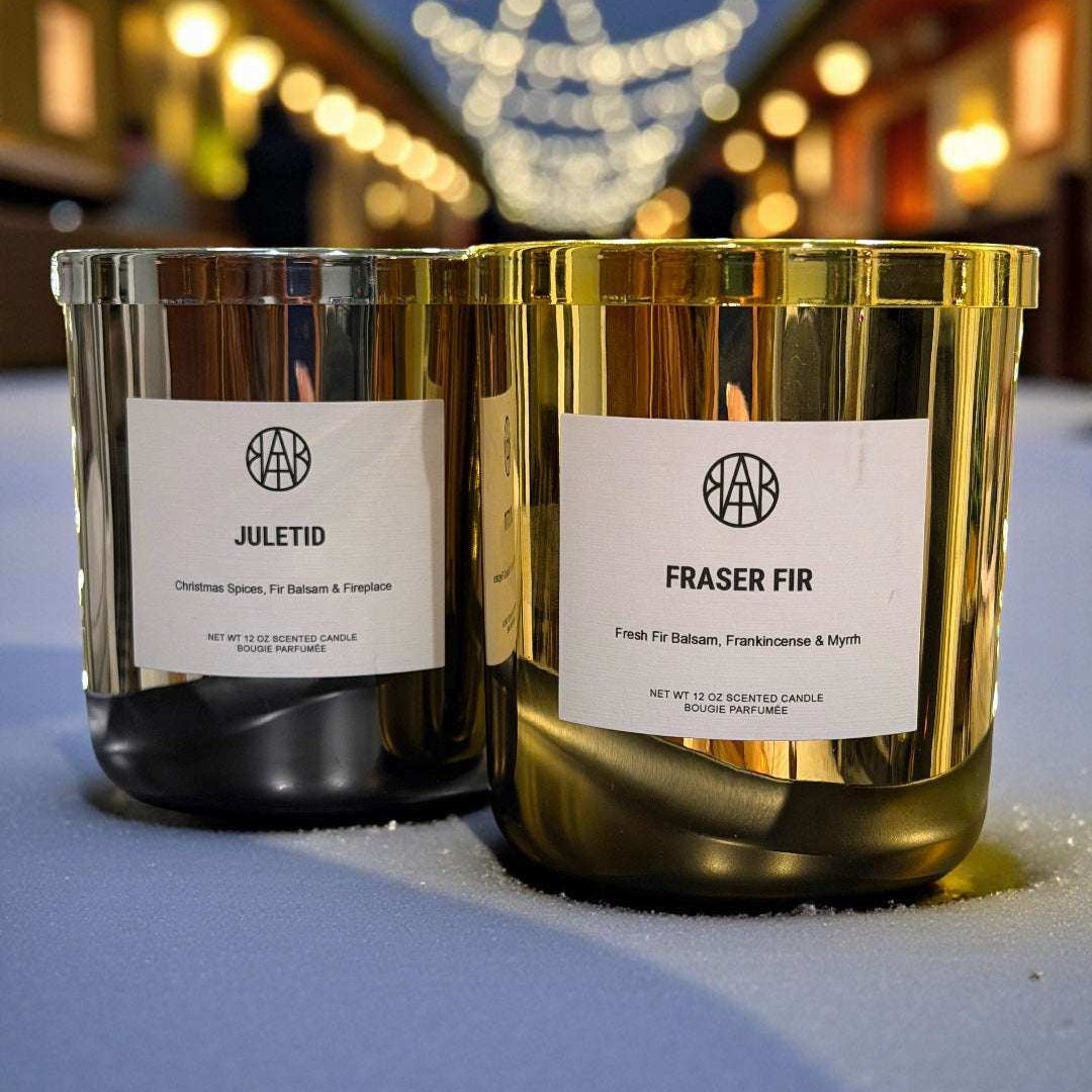 AEMBR Juletid and Fraser Fir non-toxic candles in gold jars on a festive outdoor table with string lights