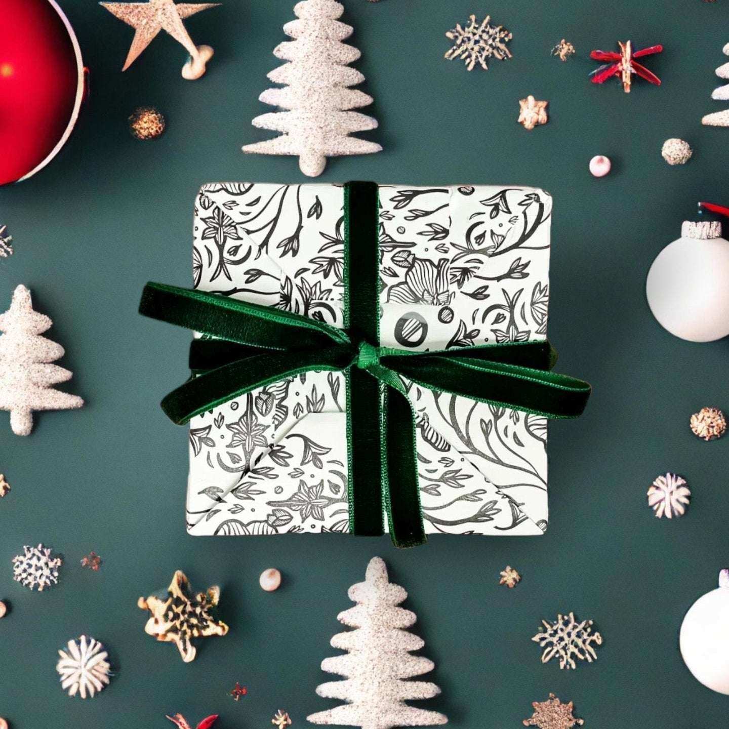 AEMBR holiday gift box with botanical wrap and green velvet ribbon, surrounded by festive decor.