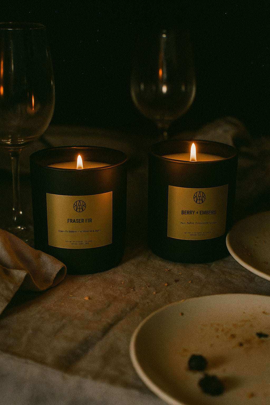 AEMBR non-toxic candles lit on a cozy dinner table with empty wine glasses and plates