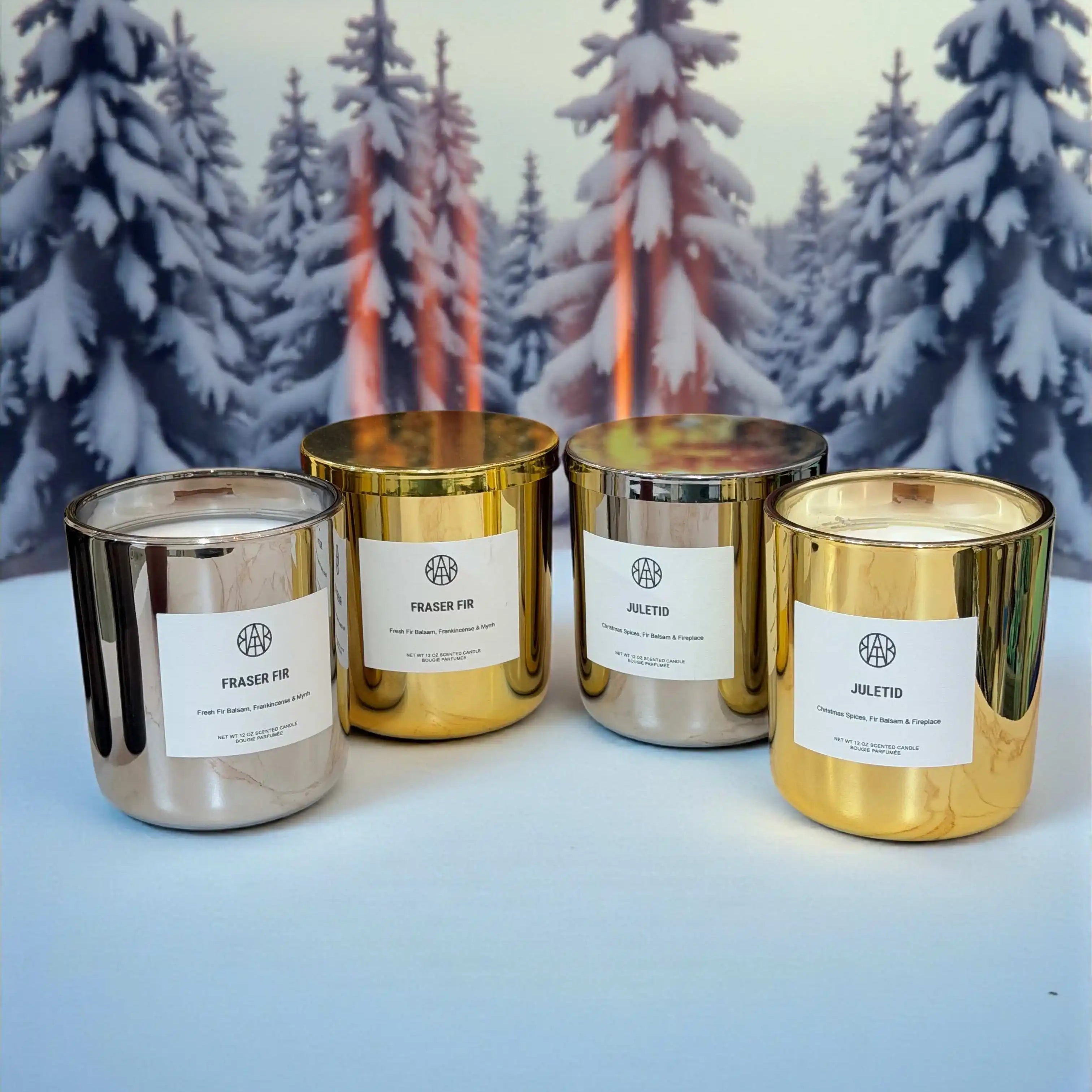 AEMBR silver and gold candles on white surface with snowy pine trees background