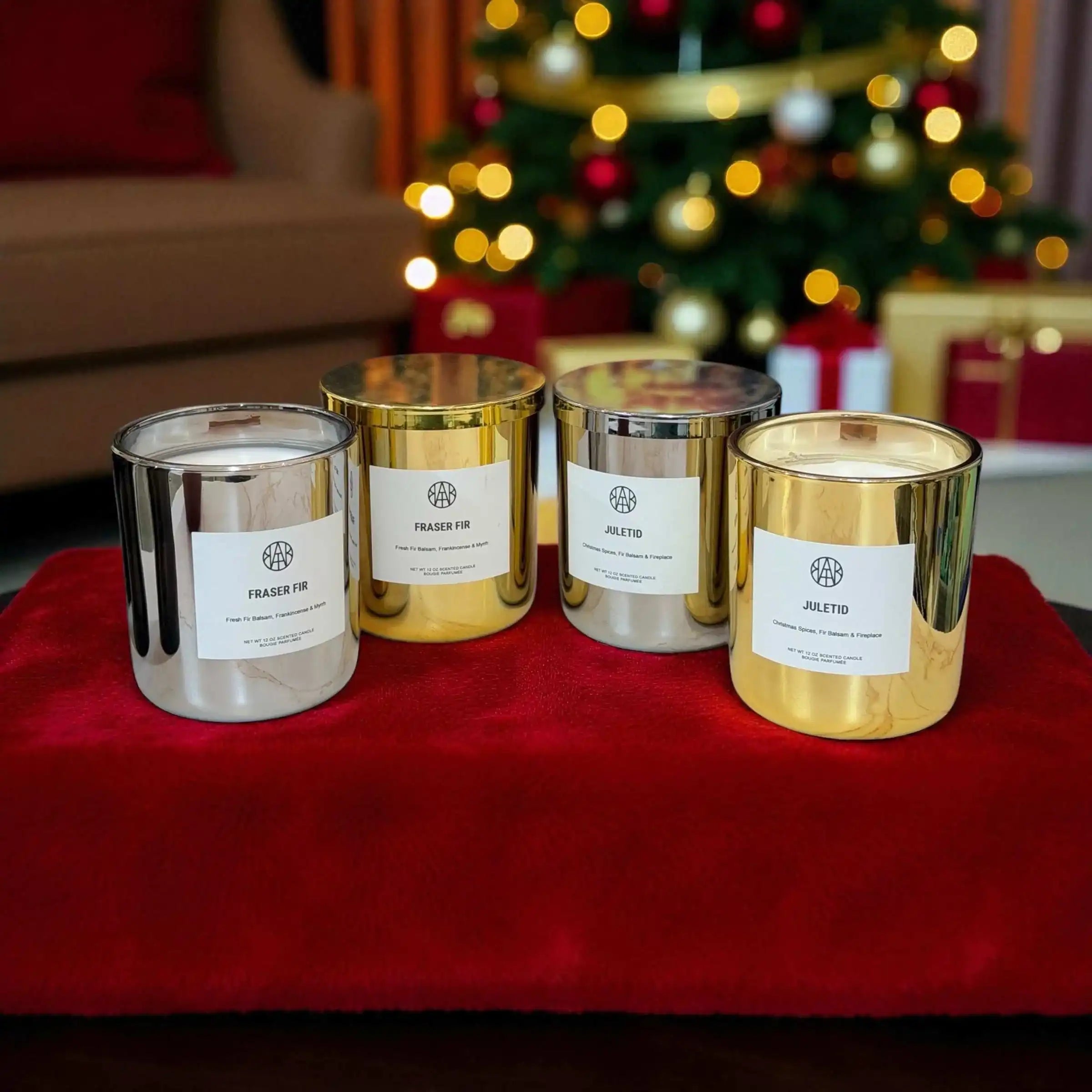 AEMBR silver and gold holiday candles on red velvet, Christmas tree and gifts in background