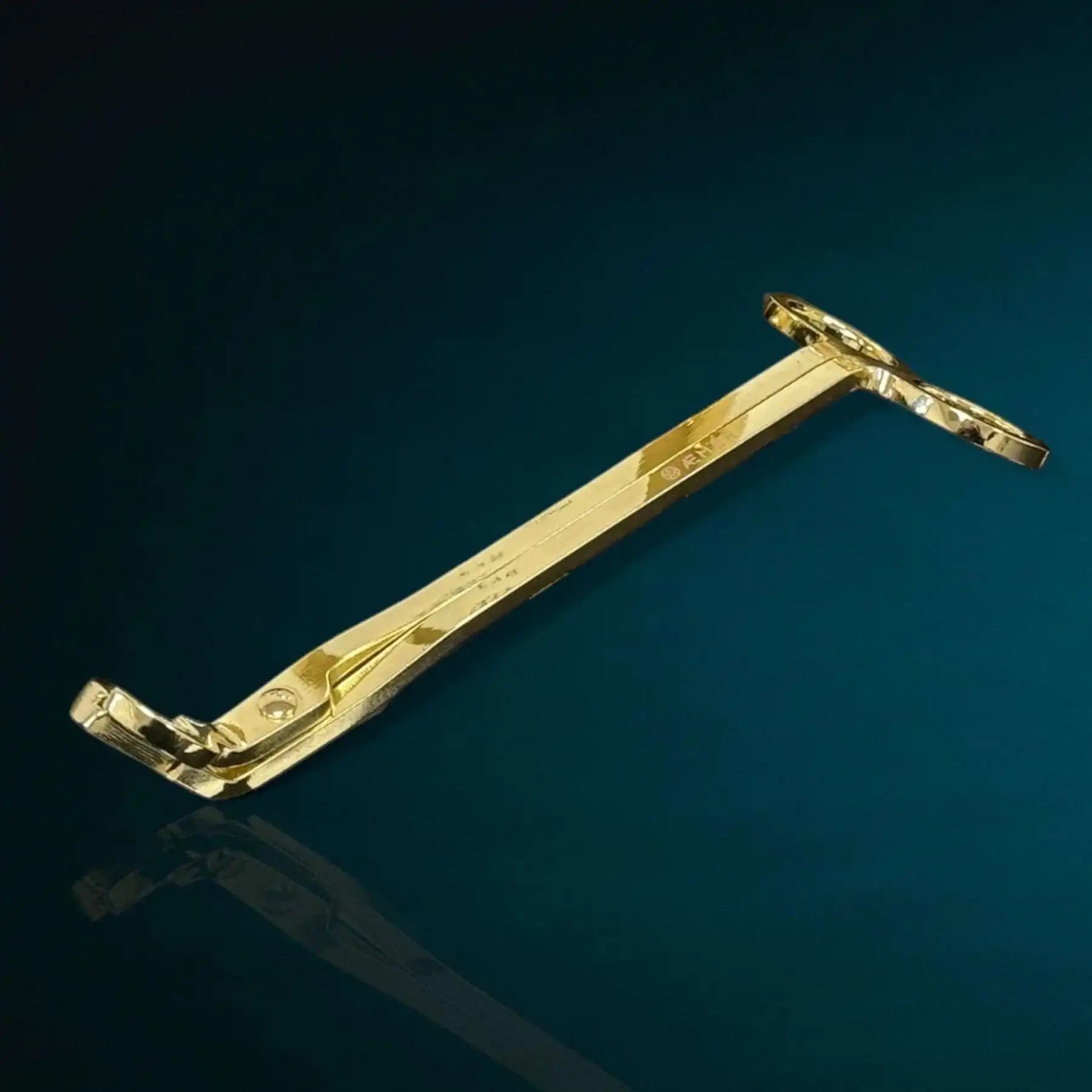 AEMBR gold candle wick trimmer on a dark blue background, luxury candle accessory