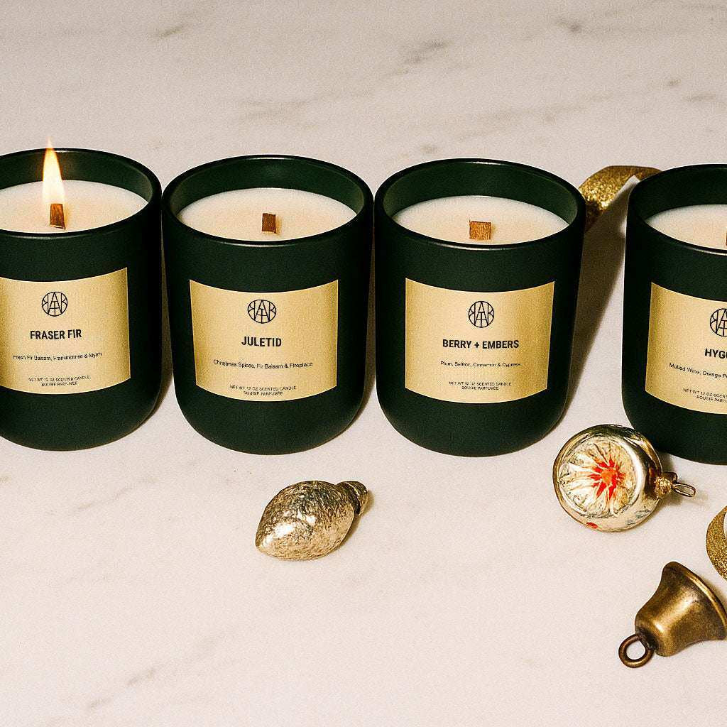 AEMBR winter collection non-toxic candles in green jars on marble with gold ornaments and ribbon