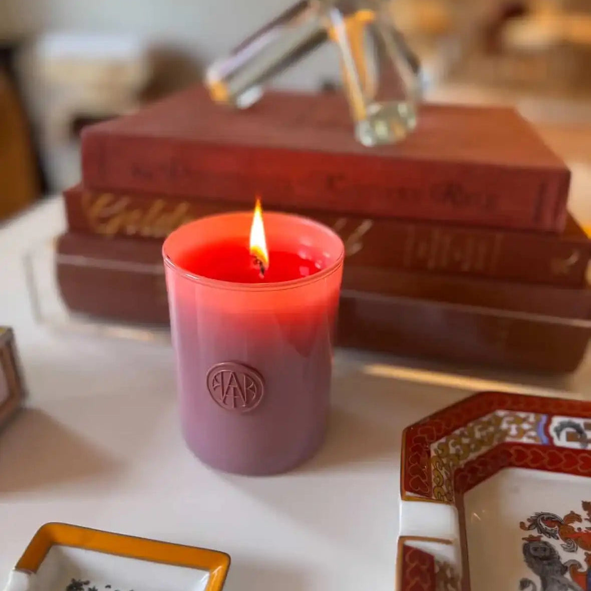 AEMBR non-toxic vegan candle burning on a table with books and decorative trays