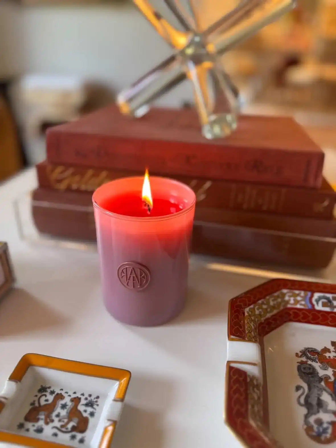 AEMBR non-toxic vegan candle burning on a table with books and decorative trays