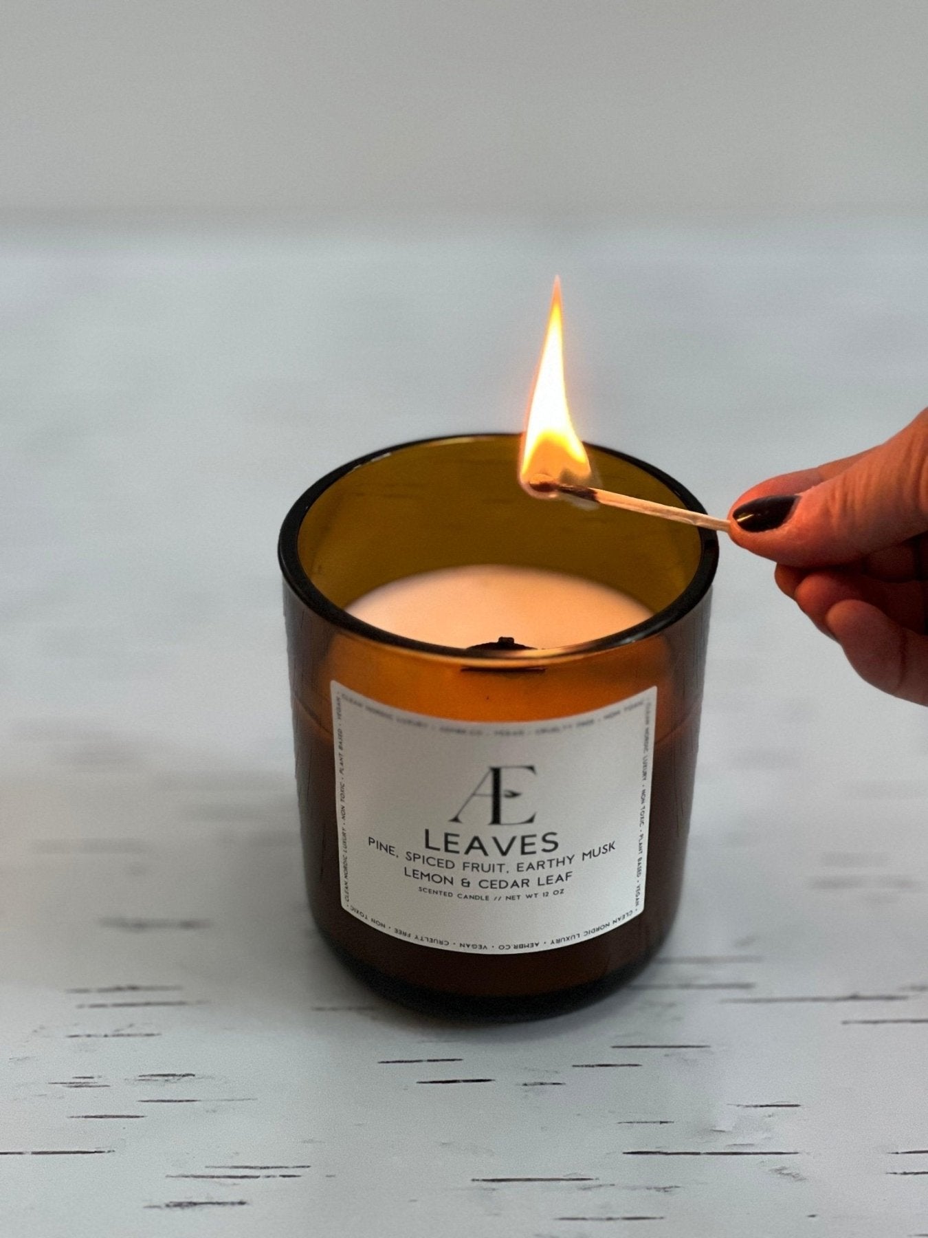 Hand lighting non-toxic scented candle with wooden wick in amber glass jar