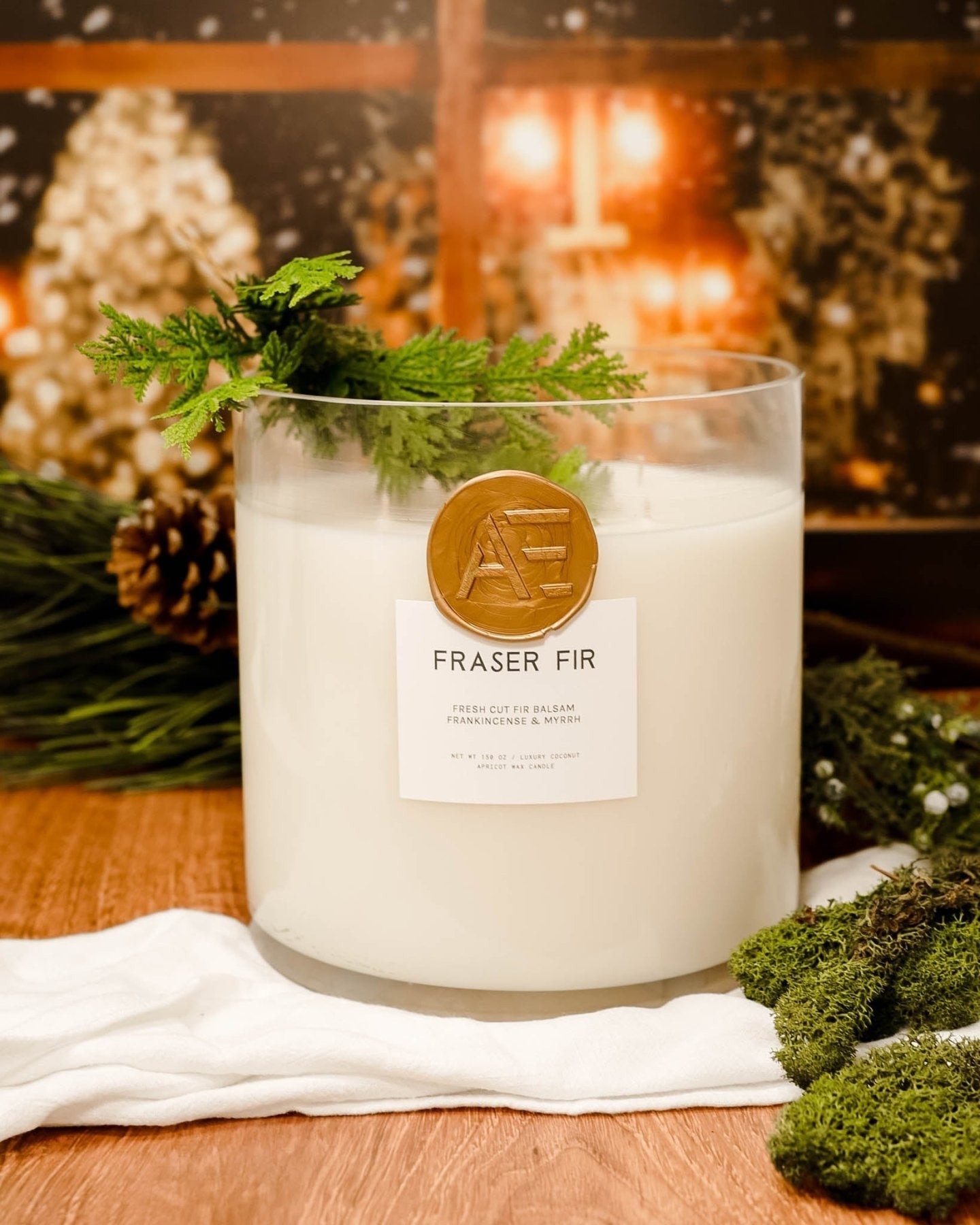 AEMBR Fraser Fir luxury scented candle on wood, surrounded by pine, greenery, and cozy holiday decor.