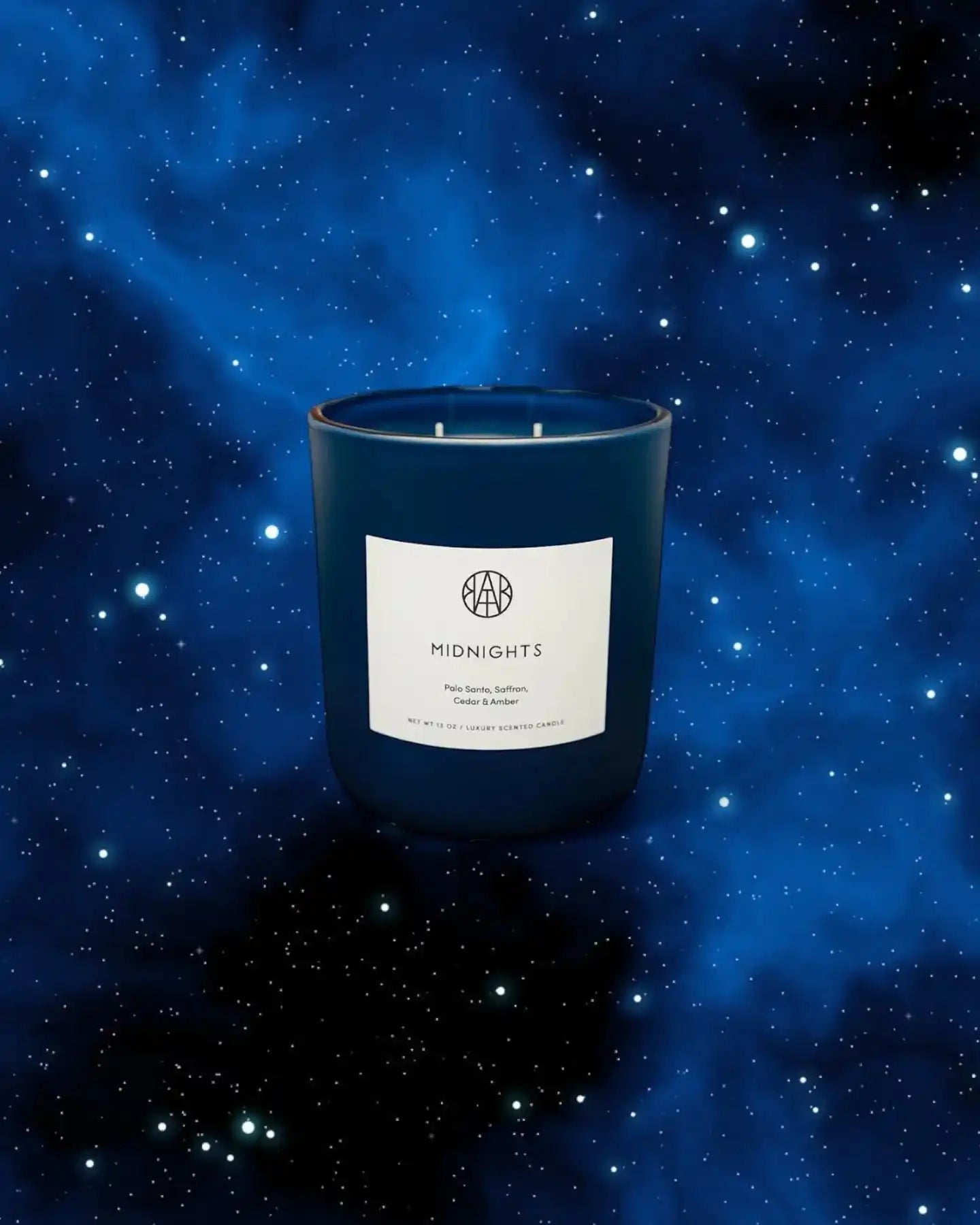 Non-toxic luxury scented candle in navy glass jar labeled 'Midnights' with a starry night sky background