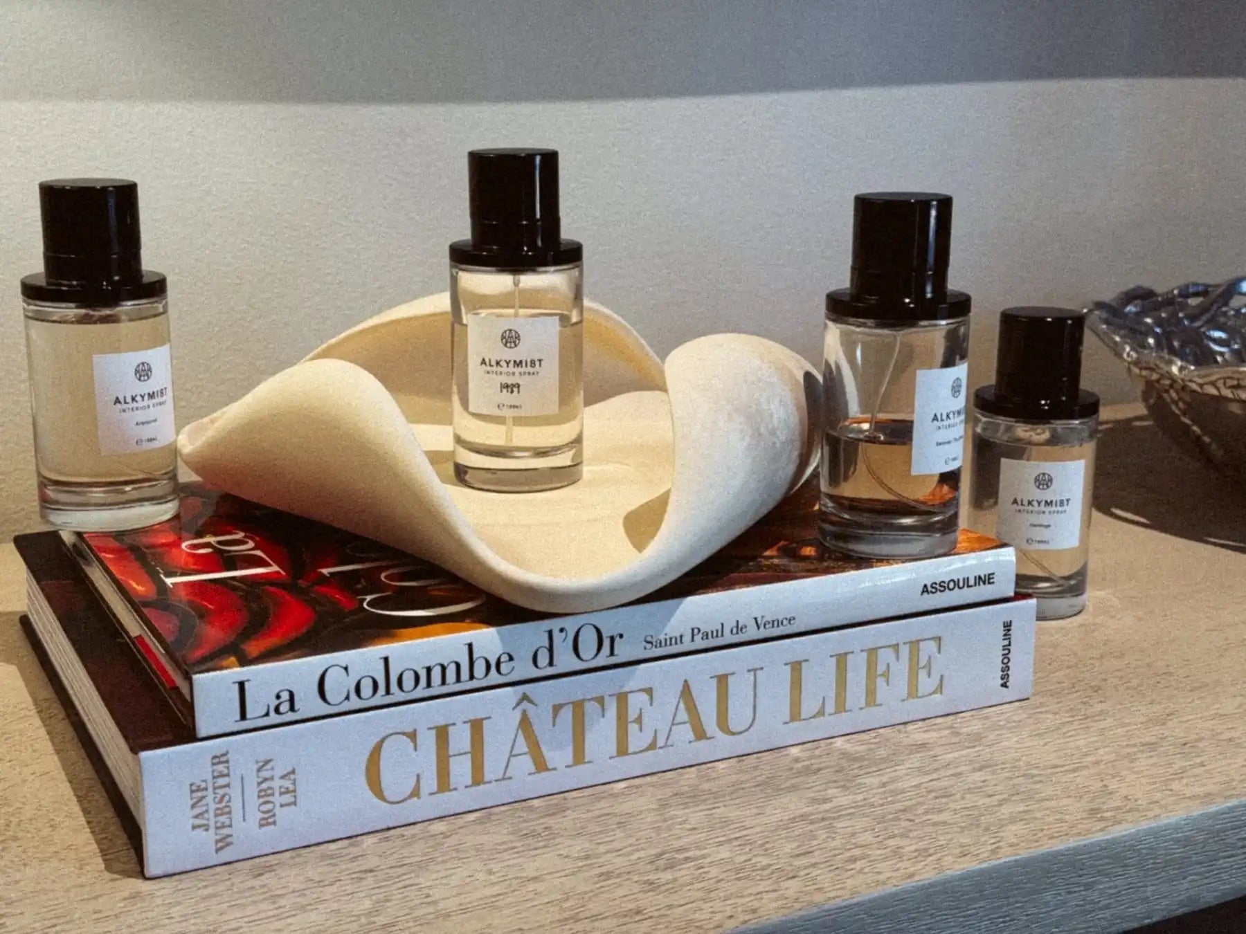 Alkymist interior sprays displayed on books with modern decor, non-toxic home fragrance