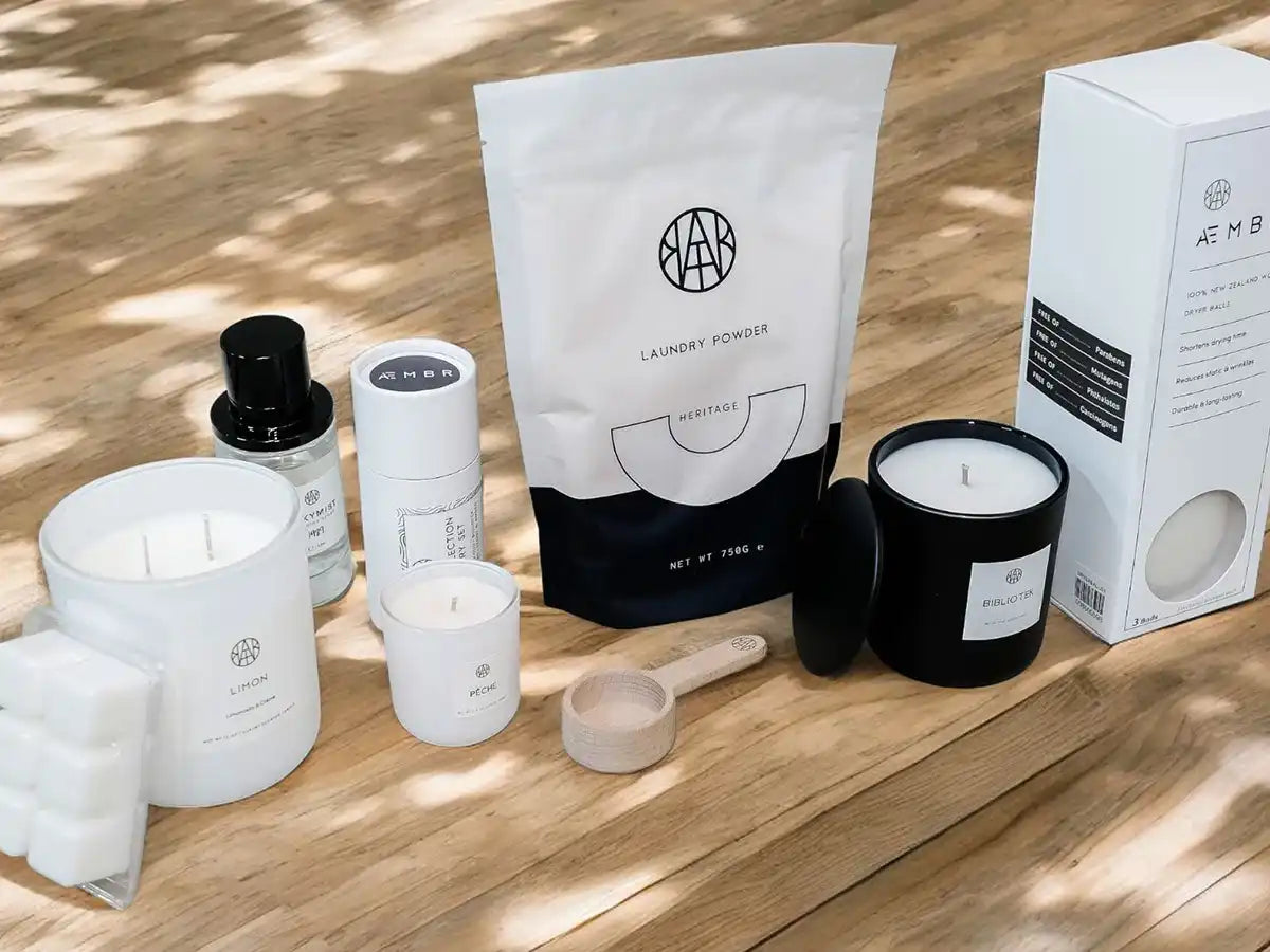 AEMBR non-toxic scented candles, laundry powder, and home essentials on wooden table