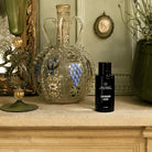 AEMBR Lavender Haze Alkymist fragrance bottle on a mantel with ornate glass decor