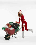 AEMBR holiday image: smiling woman in Santa outfit pushing wheelbarrow full of wrapped gifts.