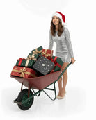 Woman in silver dress and Santa hat with wheelbarrow of holiday gift boxes, AEMBR lifestyle