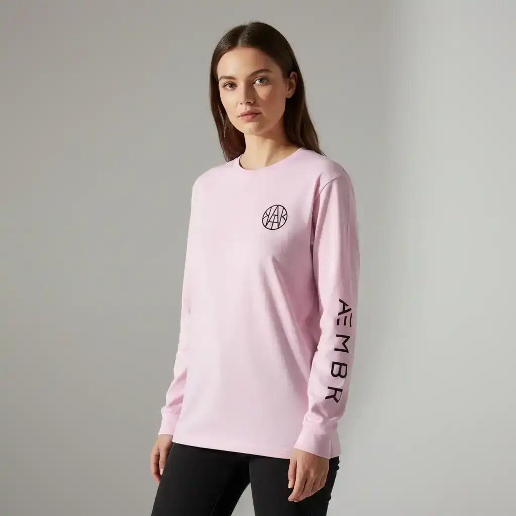 Woman wearing pink AEMBR long sleeve shirt with logo and branded sleeve, neutral background