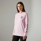 Woman wearing pink AEMBR long sleeve shirt with logo and branded sleeve, neutral background