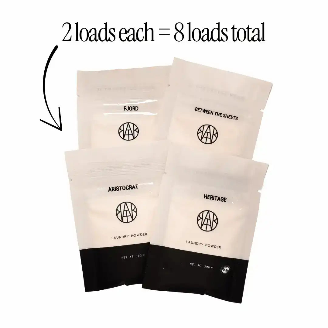AEMBR non-toxic laundry powder sample packs in four scents with text '2 loads each = 8 loads total'.