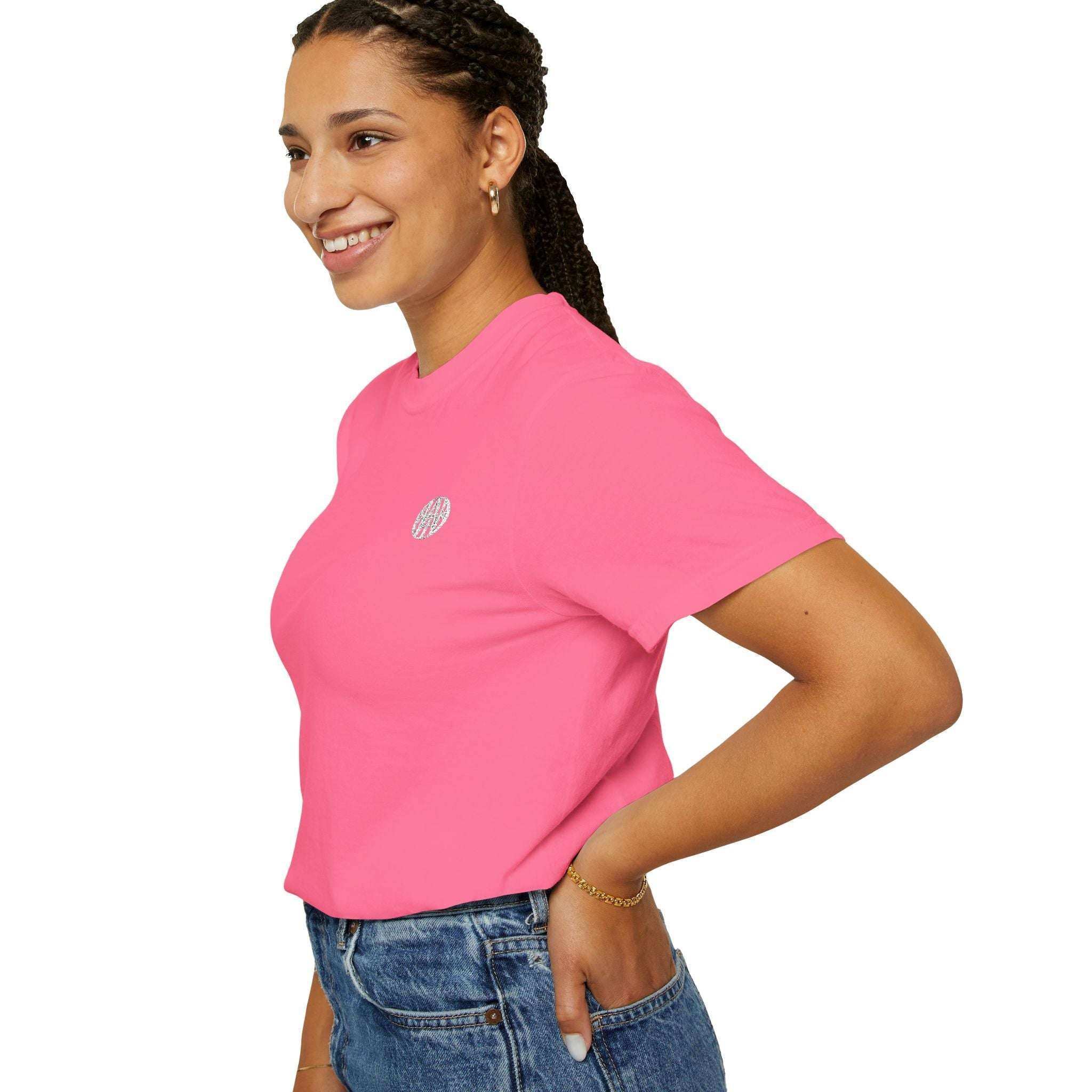 Smiling woman in pink AEMBR t-shirt with logo, wearing jeans, on white background