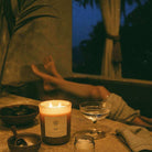 AEMBR Salt candle burning by a bath with towel, glass, and bowl in a relaxing evening setting