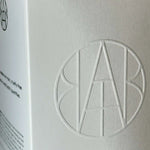 Embossed AEMBR logo on minimalist white packaging for non-toxic home products