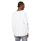 Man wearing white AEMBR long sleeve shirt with black logo on sleeve, light jeans, back view