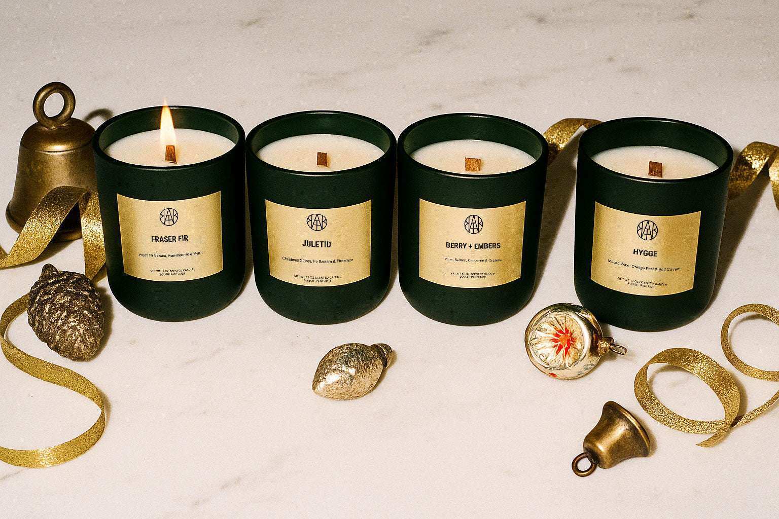 AEMBR winter collection non-toxic candles in green jars on white marble, with festive gold decor