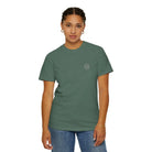 Woman wearing green AEMBR t-shirt with logo, casual jeans, minimal accessories, white background
