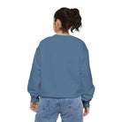 Woman wearing AEMBR blue crewneck sweatshirt and jeans, back view, plain background