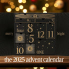 AEMBR 2025 advent calendar in black and gold with numbered drawers, festive lights in background.