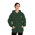 Woman wearing a dark green AEMBR hoodie with logo, hands in pocket, against white background