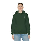 Woman wearing a dark green AEMBR logo hoodie and blue jeans on white background.