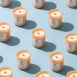 AEMBR Cloudberry non-toxic scented candles in peach glass jars arranged on a blue background