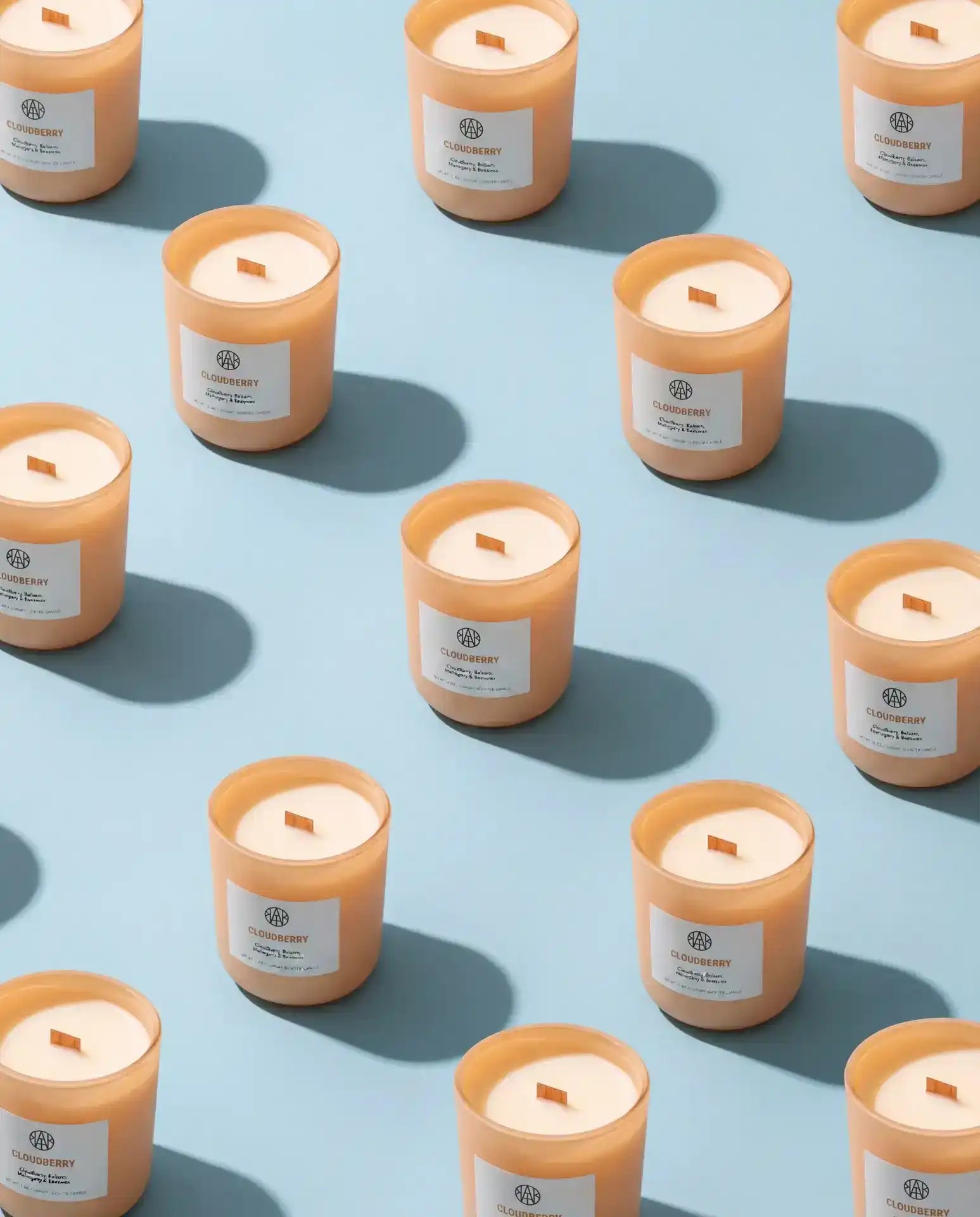 AEMBR Cloudberry candles in peach jars arranged on a blue background, eco-friendly home decor