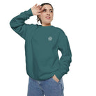 Woman wearing teal AEMBR logo sweatshirt and blue jeans against white background