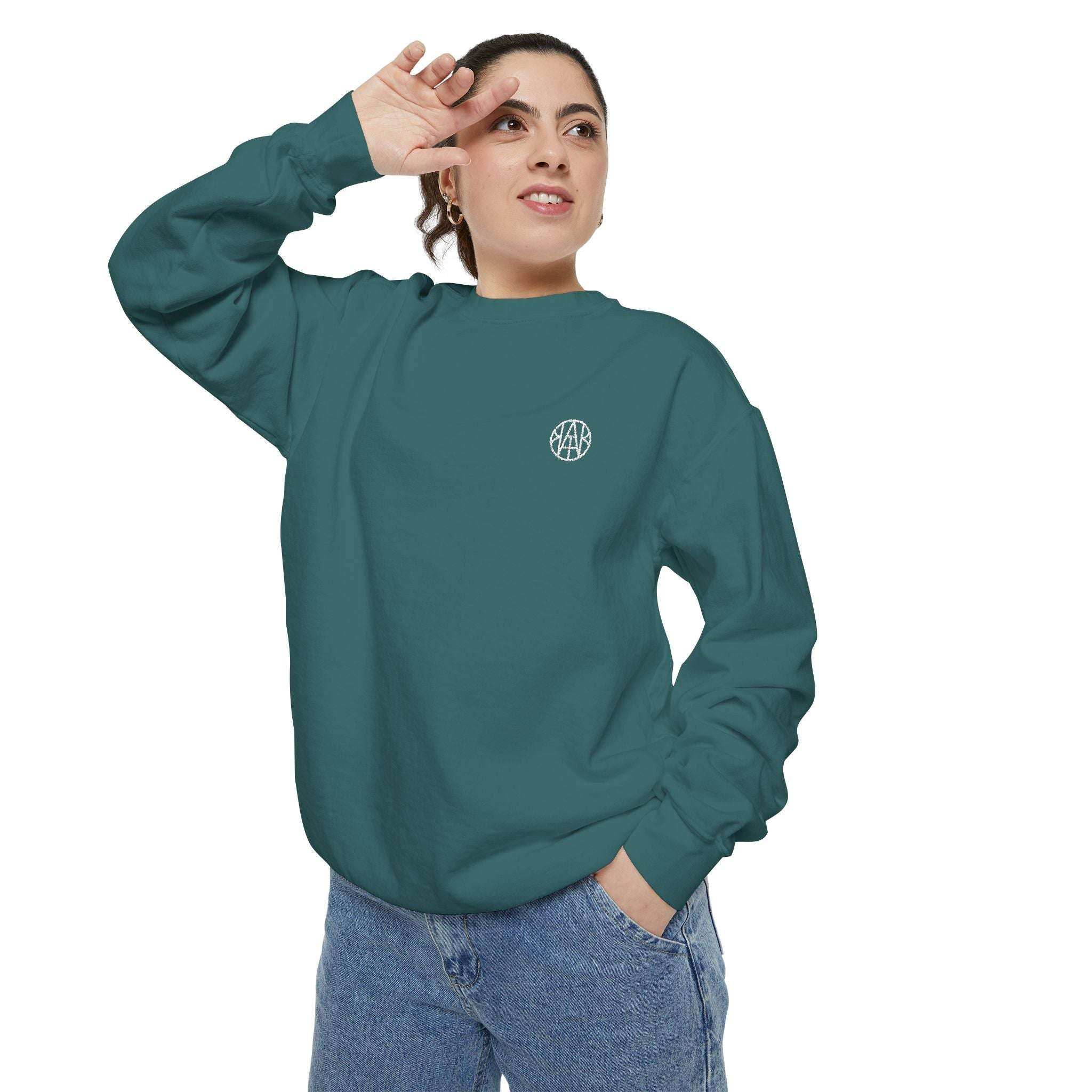 Woman wearing teal AEMBR logo sweatshirt and blue jeans against white background